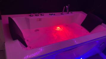 Une baignoire blanche avec une lumière rouge, un robinet et un panneau de commande.