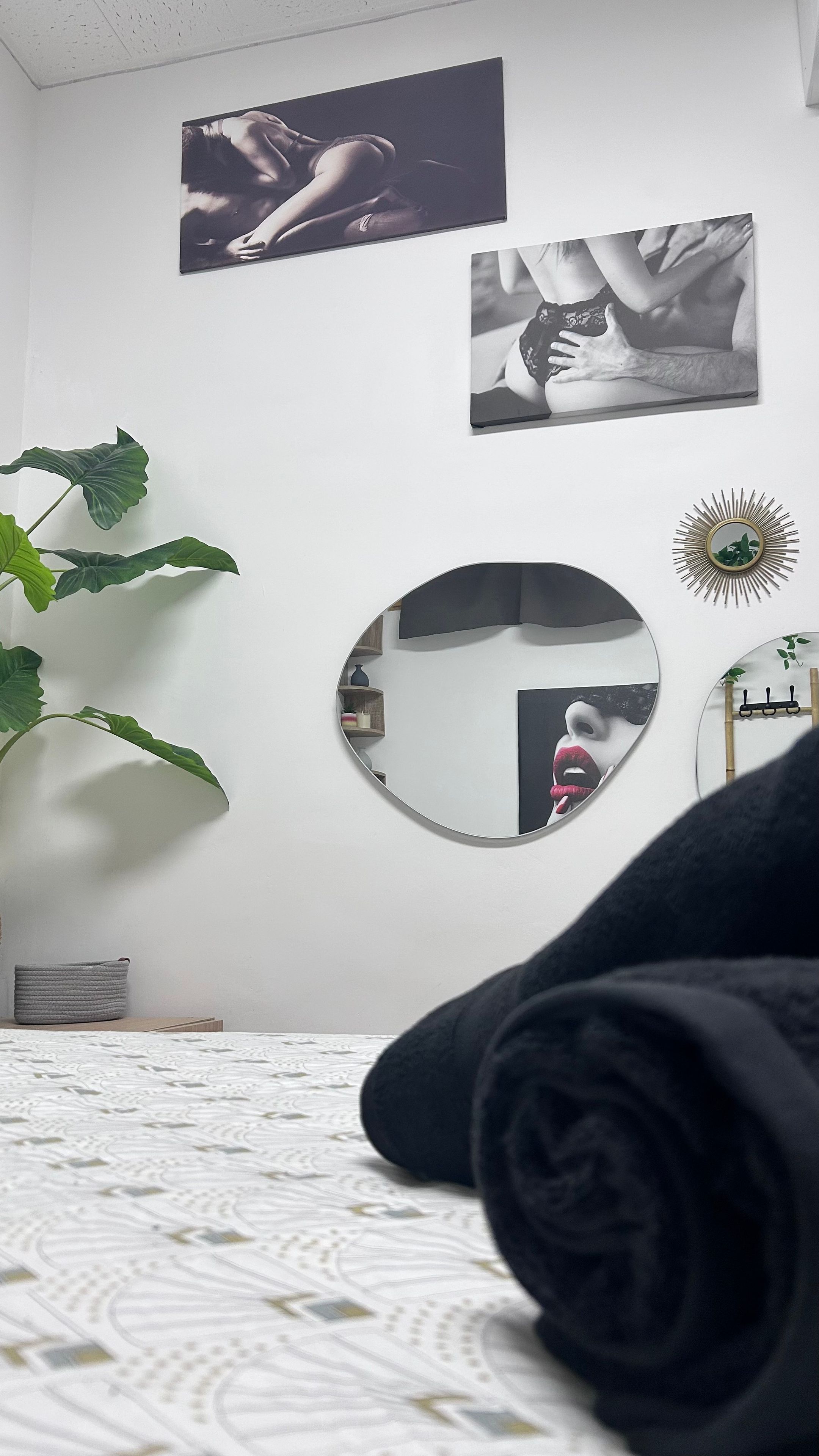 A bedroom with a bed, a round mirror, and two wall-mounted photographs.