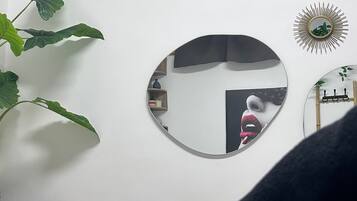 A bedroom with a bed, a round mirror, and two wall-mounted photographs.