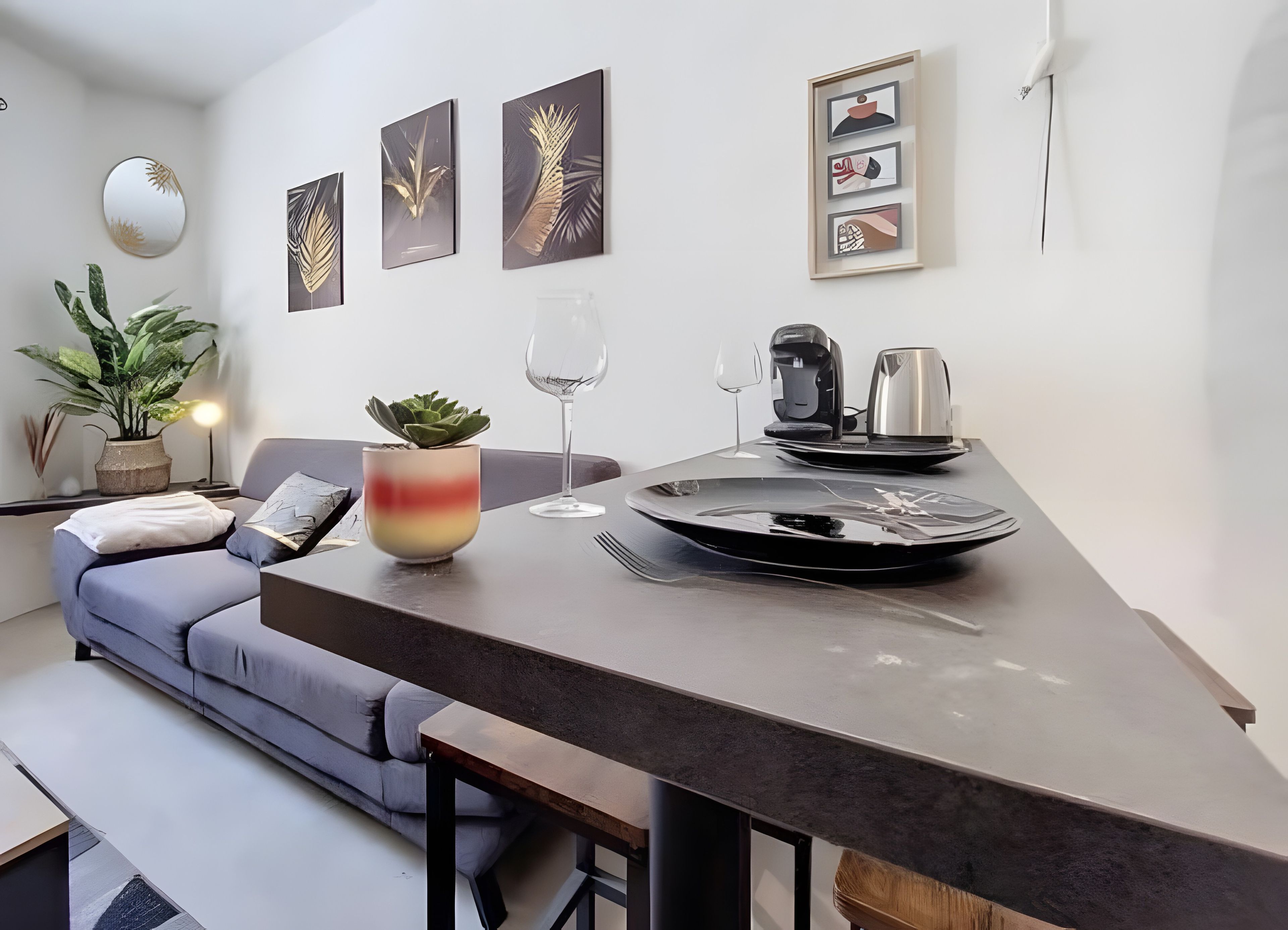 Un espace de vie moderne comprenant un canapé, une table à manger, une machine à café et un verre à vin.