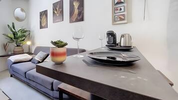 Un espace de vie moderne comprenant un canapé, une table à manger, une machine à café et un verre à vin.