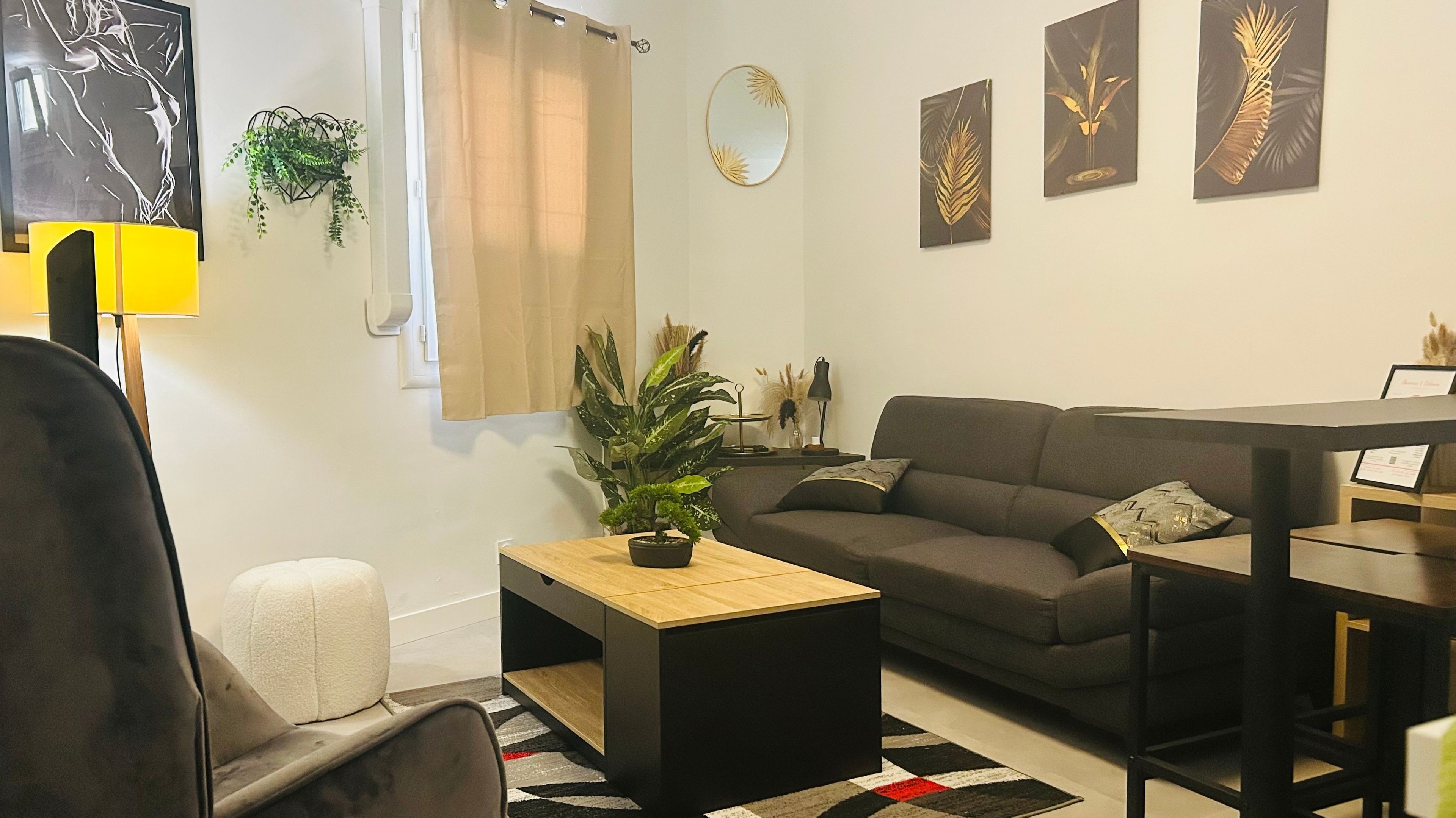Een woonkamer met een bank, een salontafel, een plant en kunst aan de muur.