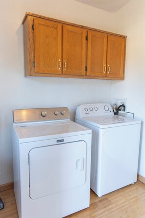 A laundry area with two white washing machines and a wooden cabinet above.