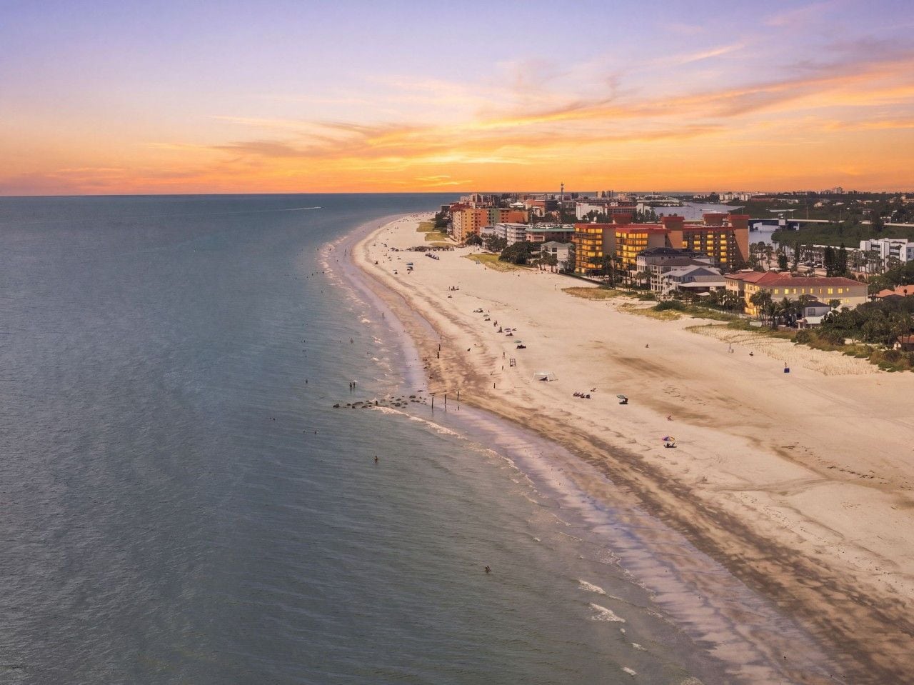 Eine Küstenstadtlandschaft mit Strand, Gebäuden und Sonnenuntergang.