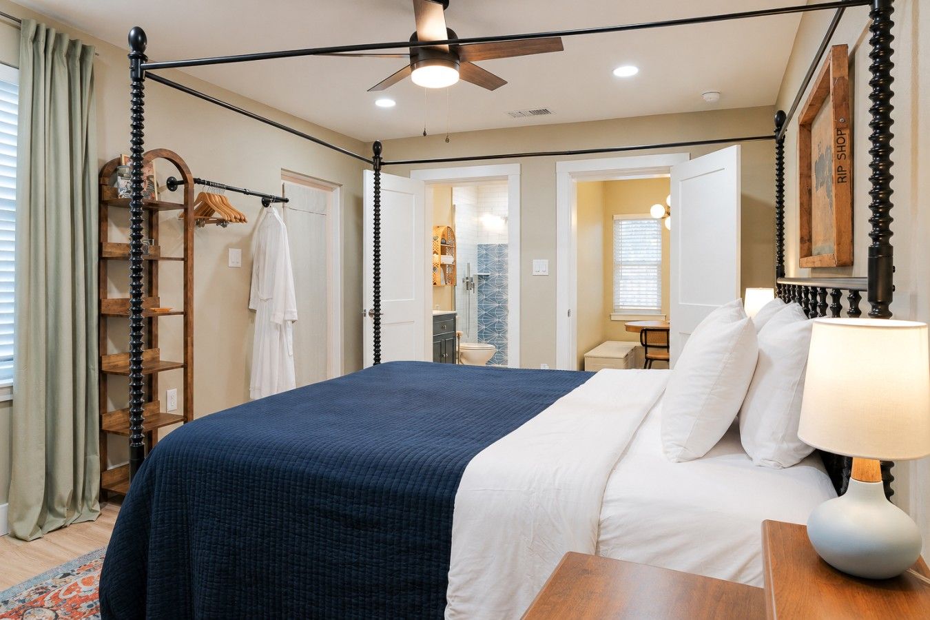 A bedroom with a bed, a bedside table, a lamp, a wardrobe, and a ceiling fan.
