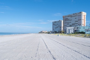 Une vaste plage de sable, avec des bâtiments en arrière-plan.