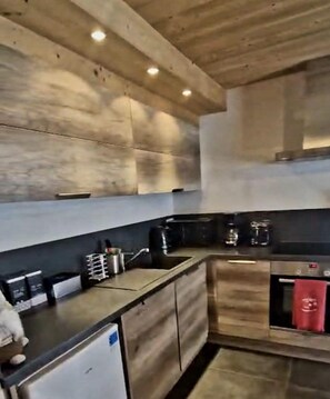 A modern kitchen with wooden cabinets, a black countertop, and a built-in oven.