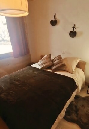 A bedroom with a bed, pillows, a lamp, and a wall-mounted decoration.