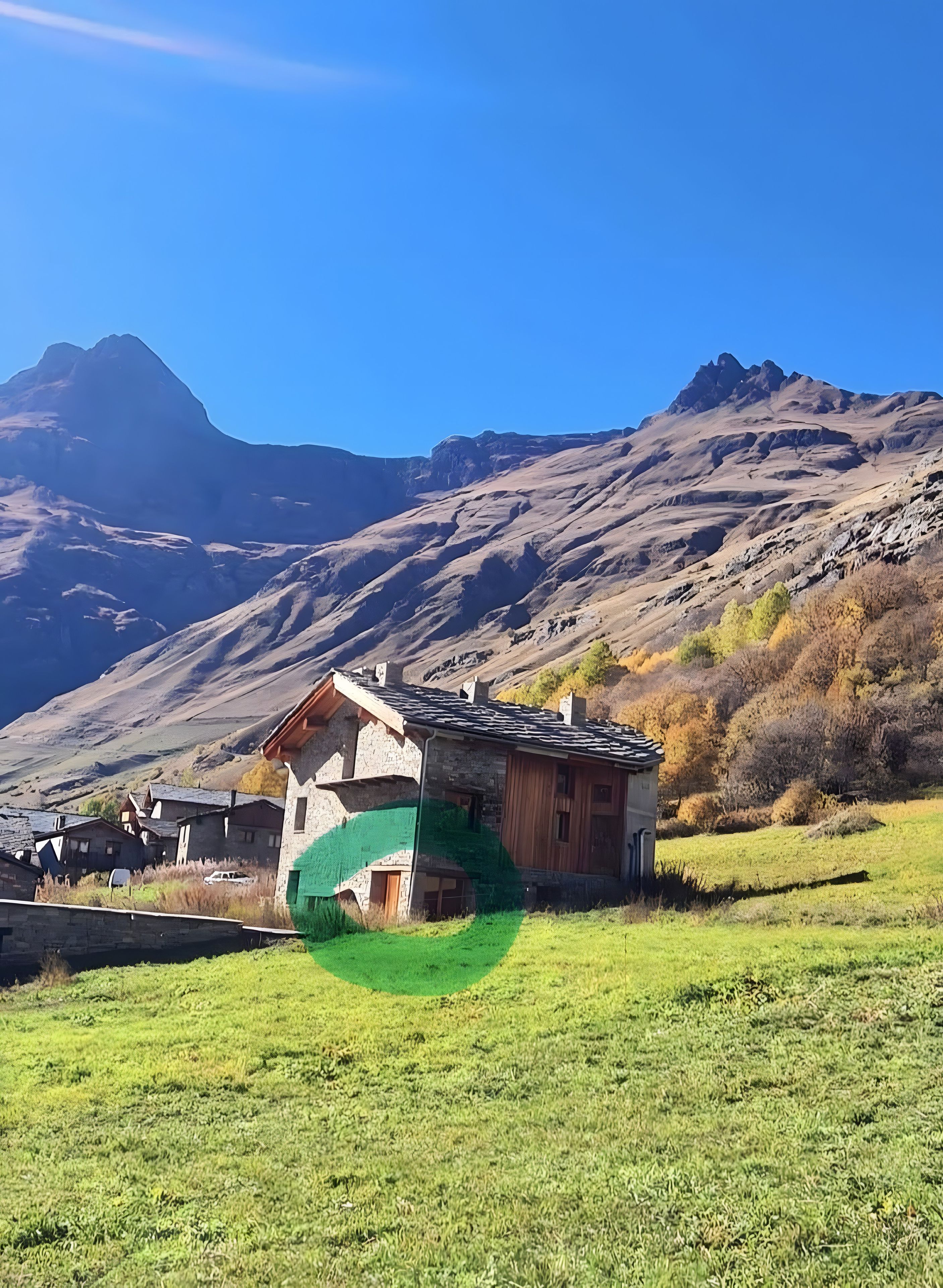 Eine Berglandschaft mit einem Steinhaus, das ein geneigtes Dach und eine grüne Plane hat.