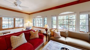 A living room with a red sofa, a beige sofa, a wooden coffee table, and a ceiling fan. - Spruce Slopeside Ski-in Access (Avon)