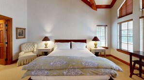 A hotel room with a large bed, two bedside tables with lamps, a chair, and a window with blinds. - Spruce Slopeside Ski-in Access (Avon)