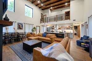 A spacious living area with a high ceiling, a dining area, and a kitchen with a central island. - Amenity-Packed! Pool, Pickleball, Sauna, Hot Tub (Broken Bow)