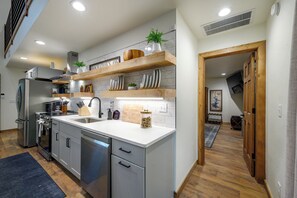 A modern kitchen with stainless steel appliances, wooden shelves, and a marble backsplash. - Amenity-Packed! Pool, Pickleball, Sauna, Hot Tub (Broken Bow)