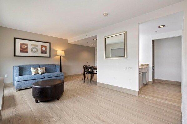 Ein modernes Wohnzimmer mit Sofa, Hocker, Esstisch und Stühlen.