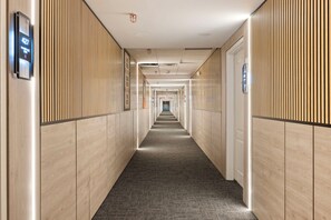 Ein Hotelkorridor mit Holzwandverkleidung, Teppichboden und einem digitalen Display, das die Zimmernummer 427 anzeigt.