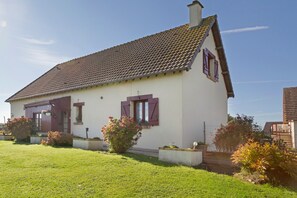 A two-story house with a tiled roof, a front door, and a small porch area.
