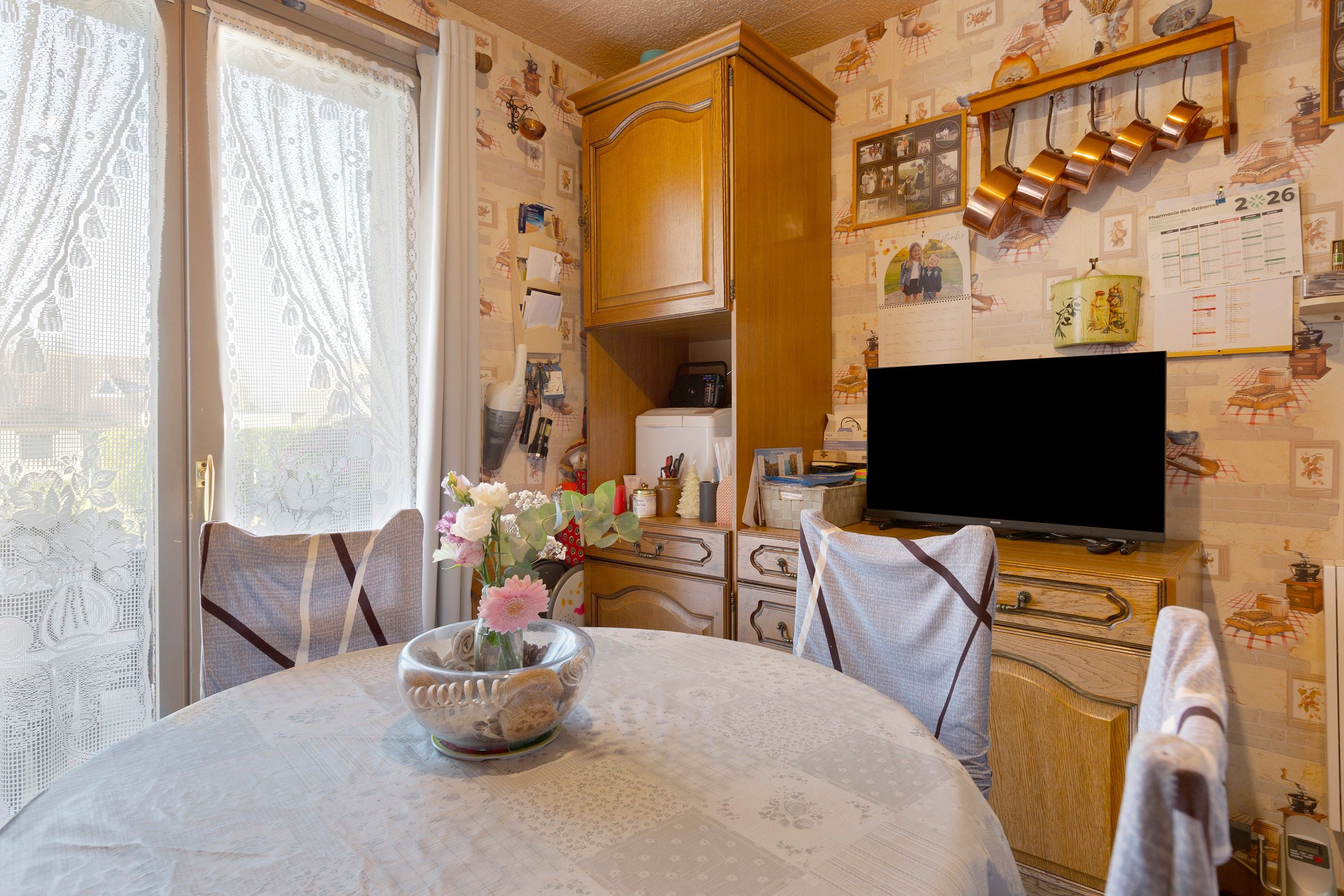 A cozy room with a dining table, chairs, a television, and a cabinet with various items.