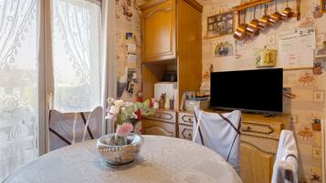 A cozy room with a dining table, chairs, a television, and a cabinet with various items.