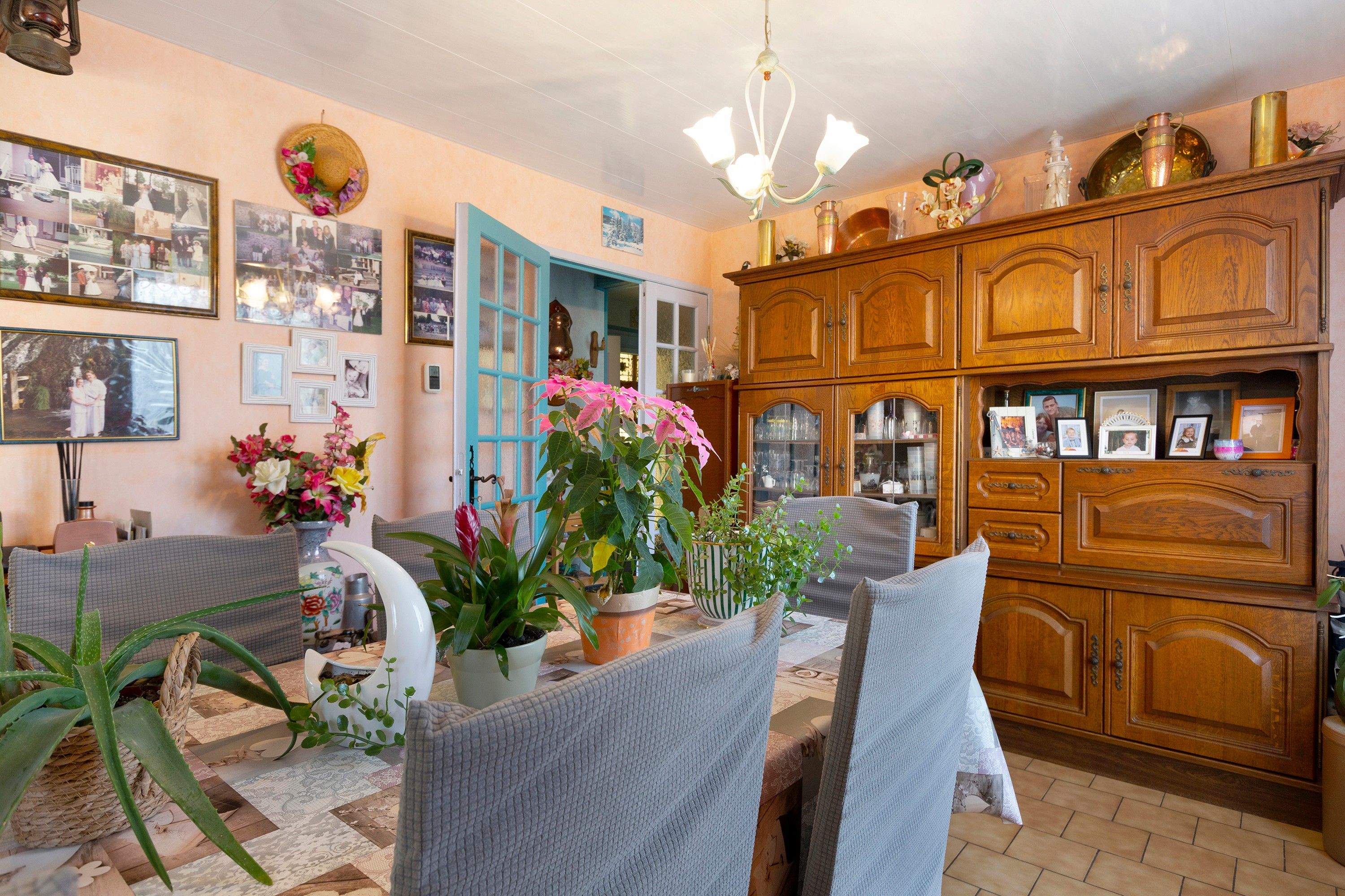 Ein gemütliches Wohnzimmer mit Essbereich, Holzschränken und verschiedenen gerahmten Fotos an den Wänden.