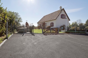A house with a tiled roof, a fenced driveway, and a clear sky.