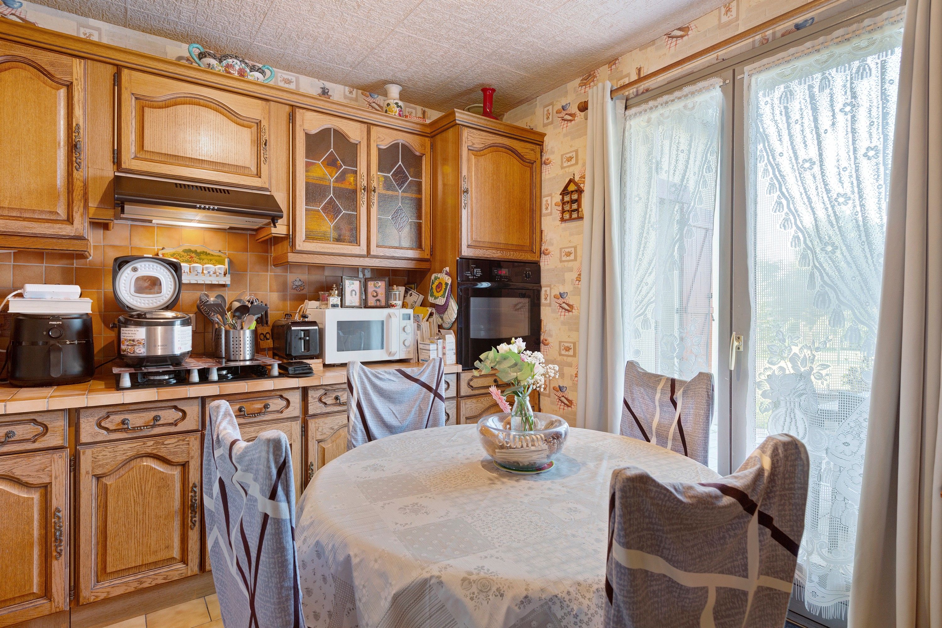 A kitchen with wooden cabinets, a stove, a microwave, and a dining table with chairs.