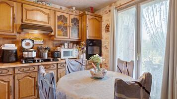 A kitchen with wooden cabinets, a stove, a microwave, and a dining table with chairs.