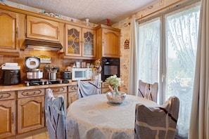 A kitchen with wooden cabinets, a stove, a microwave, and a dining table with chairs.