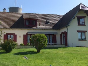 Ein zweistöckiges Haus mit einem geneigten Dach, einem kleinen Garten und einer Satellitenschüssel.