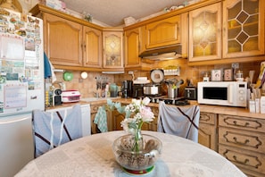 A kitchen with wooden cabinets, a microwave, and various kitchen appliances.