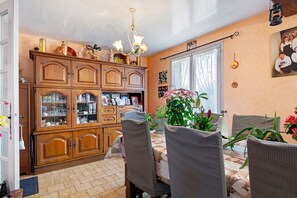 A dining area with a wooden cabinet, a chandelier, and a table with chairs.