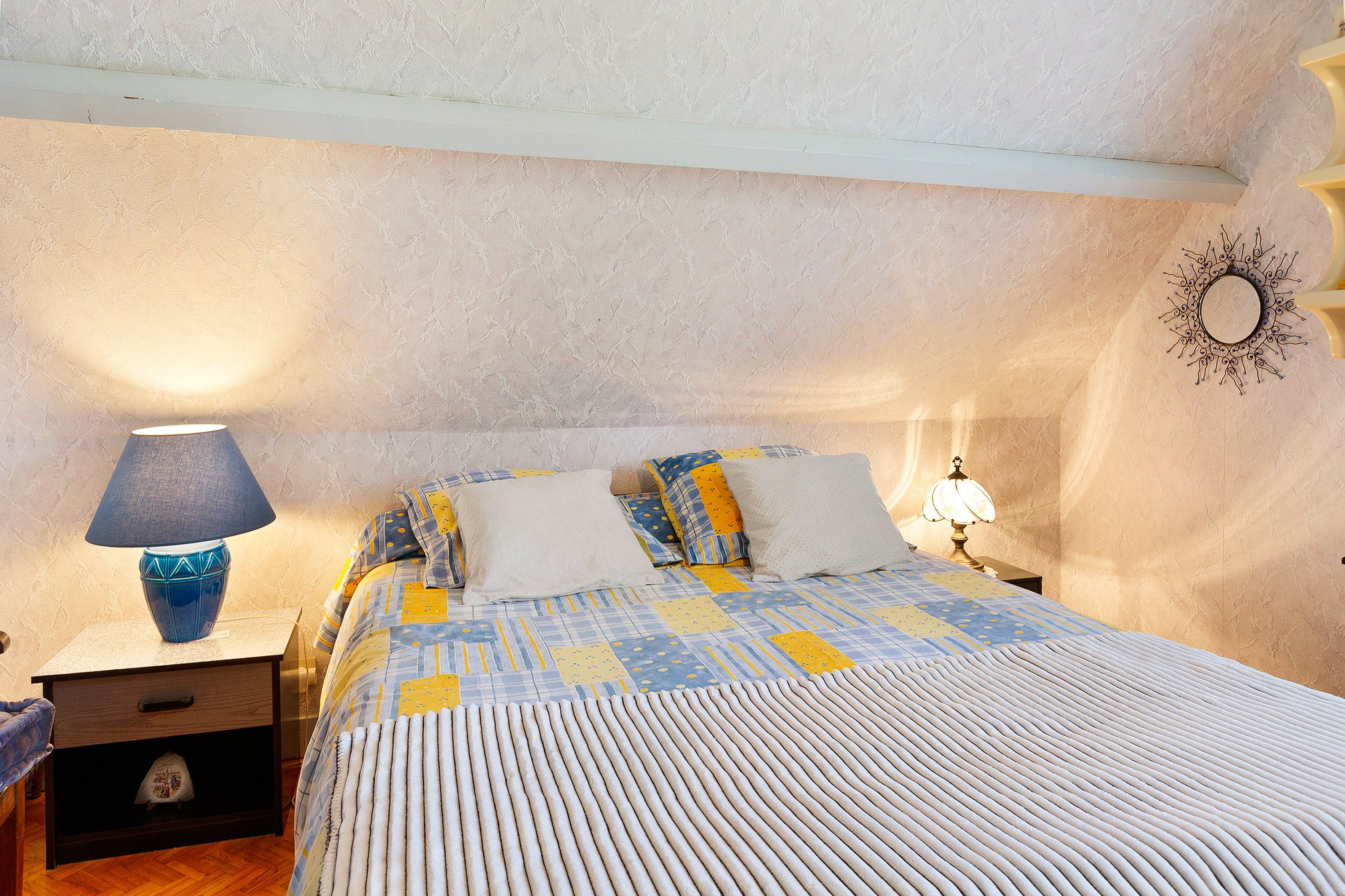 Una camera da letto con un letto, due lampade da comodino, un comodino e un elemento decorativo a parete.
