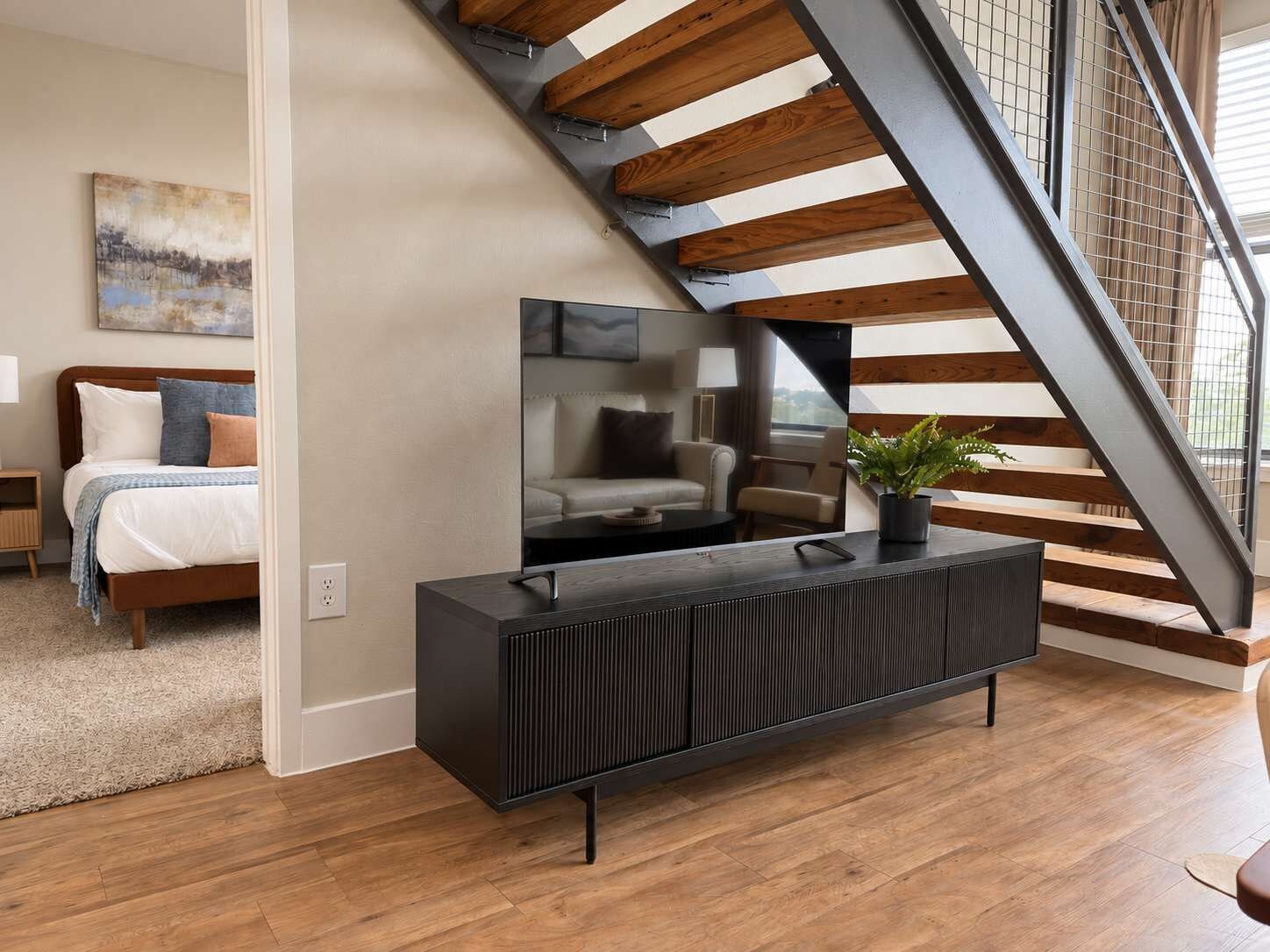 A modern living room with a wooden staircase, a black console table, and a sofa.