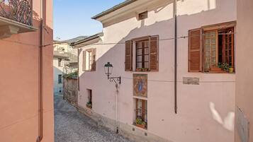 A narrow street with buildings featuring traditional shutters and a street lamp.
