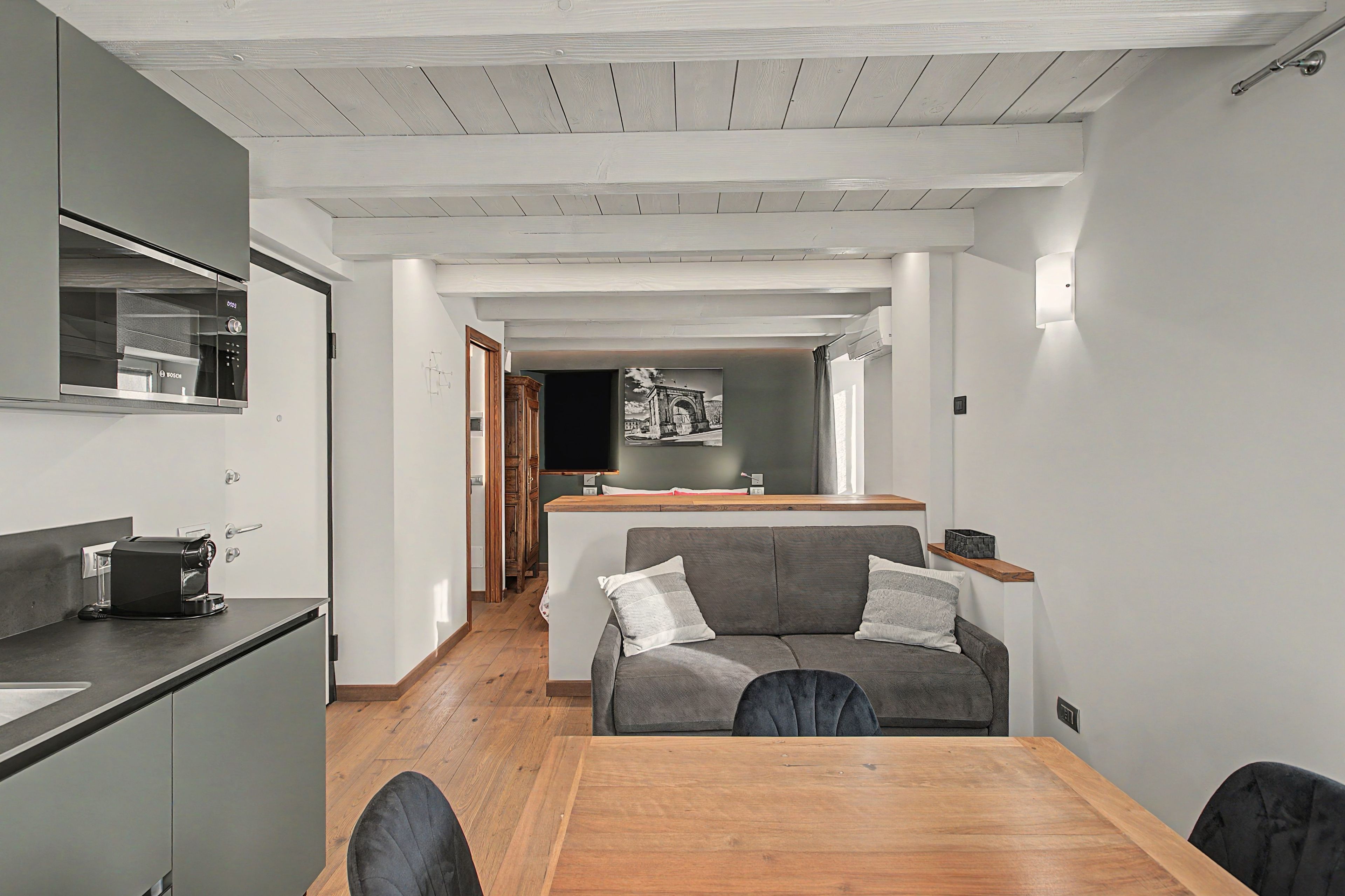 A compact living space with a kitchenette, a dining area, and a sofa.