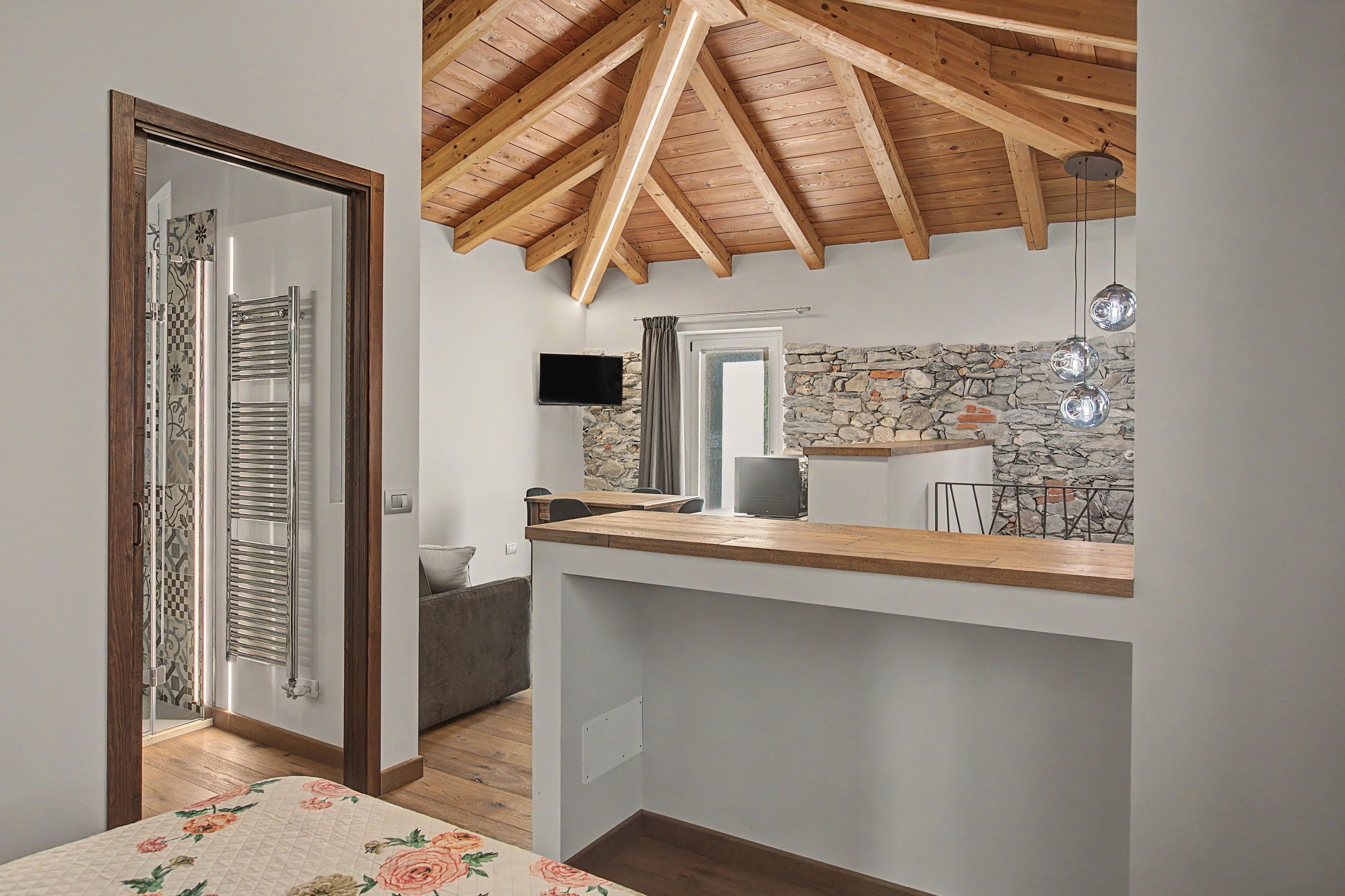 Una cocina moderna con techo de madera, pared de piedra y televisor de pantalla plana.