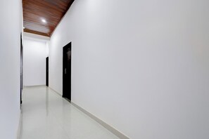 Un pasillo con techo de madera, paredes blancas y una puerta negra.