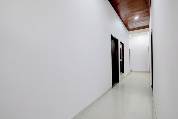A corridor with white walls and a wooden ceiling, leading to a door with a window.