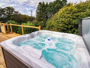 A hot tub on a wooden deck with a wooden fence and greenery in the background. - Hedley Dene Cottage (Morpeth)