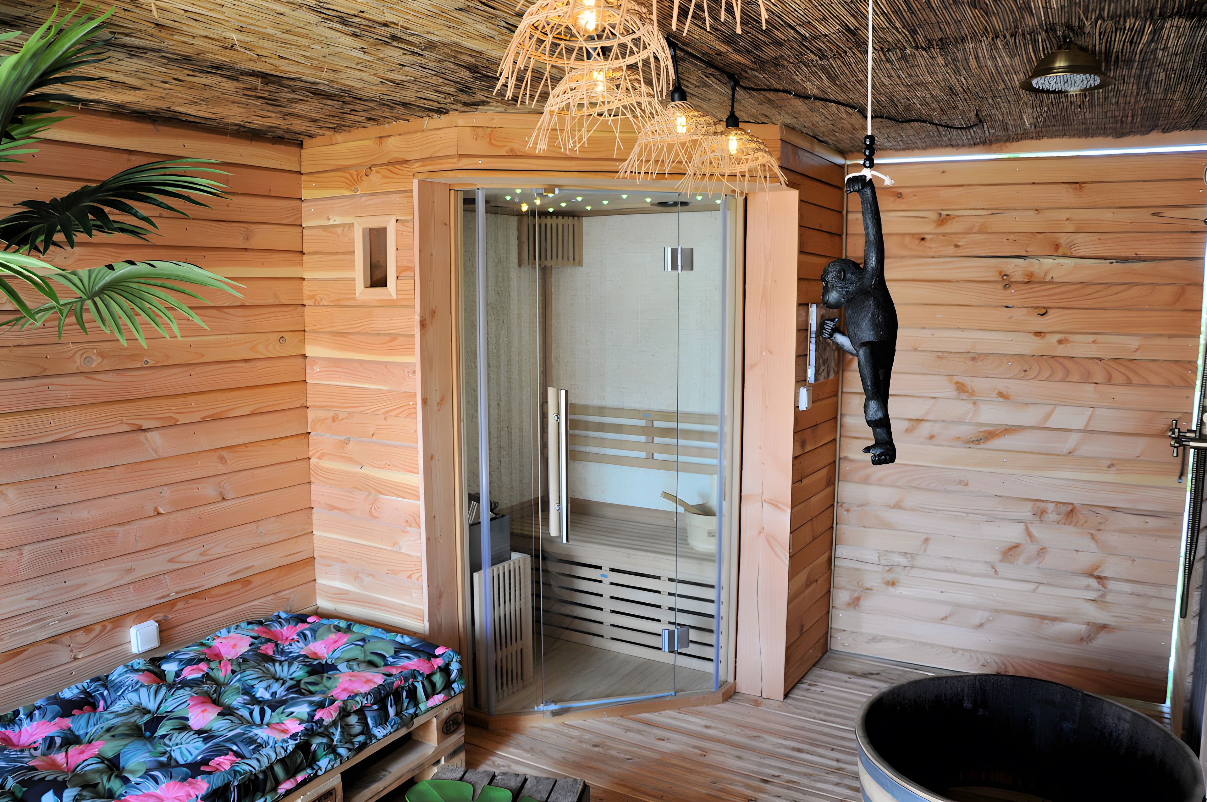 Een houten kamer met een glazen deur naar een badkamer, een hangende aap-decoratie en een bed met een bloemenbedekking.
