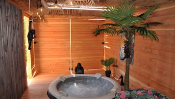 Ein Zimmer mit Holzboden, einer Badewanne, einer Statue und einer Pflanze.