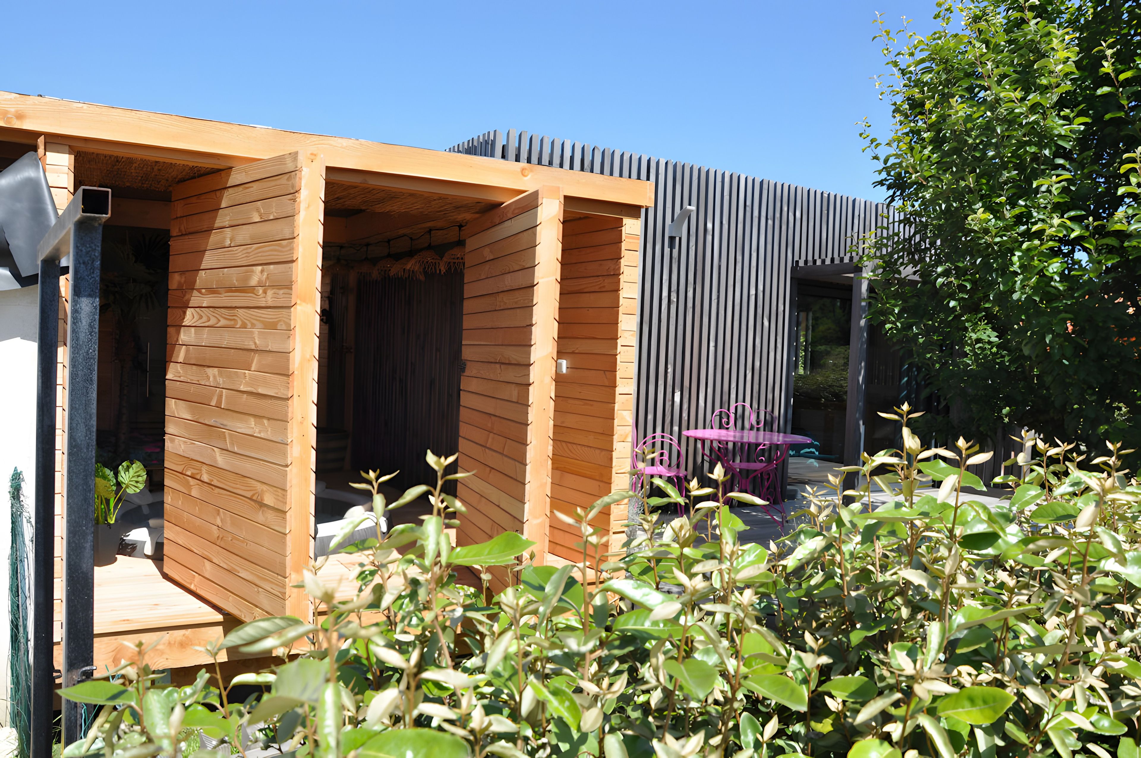 A wooden structure with a door, a metal table, and a bench.