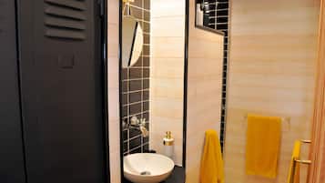 Un baño con una puerta negra, un lavabo blanco, un espejo y una toalla amarilla.