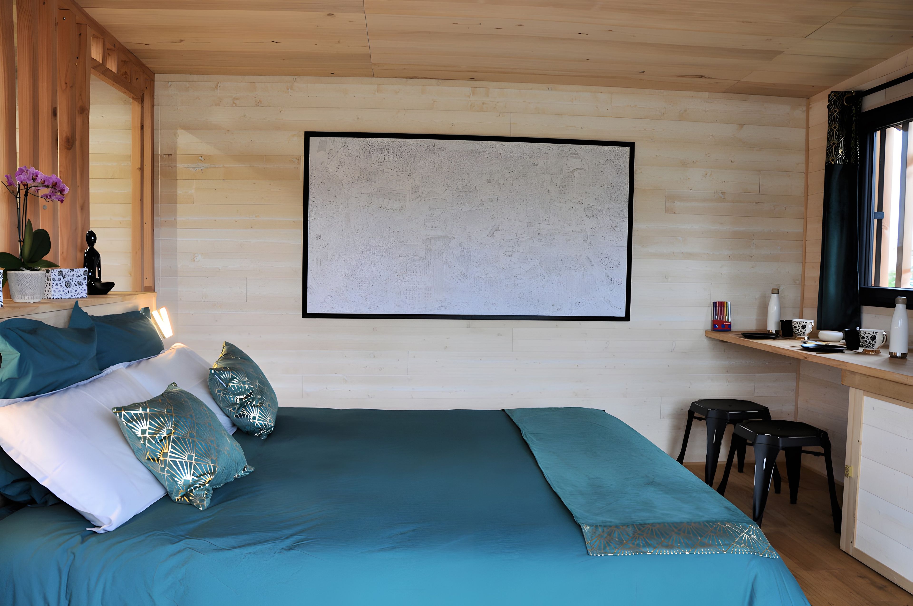 Een slaapkamer met een bed, kussens, een nachtkastje, een raam en een kunstwerk aan de muur.