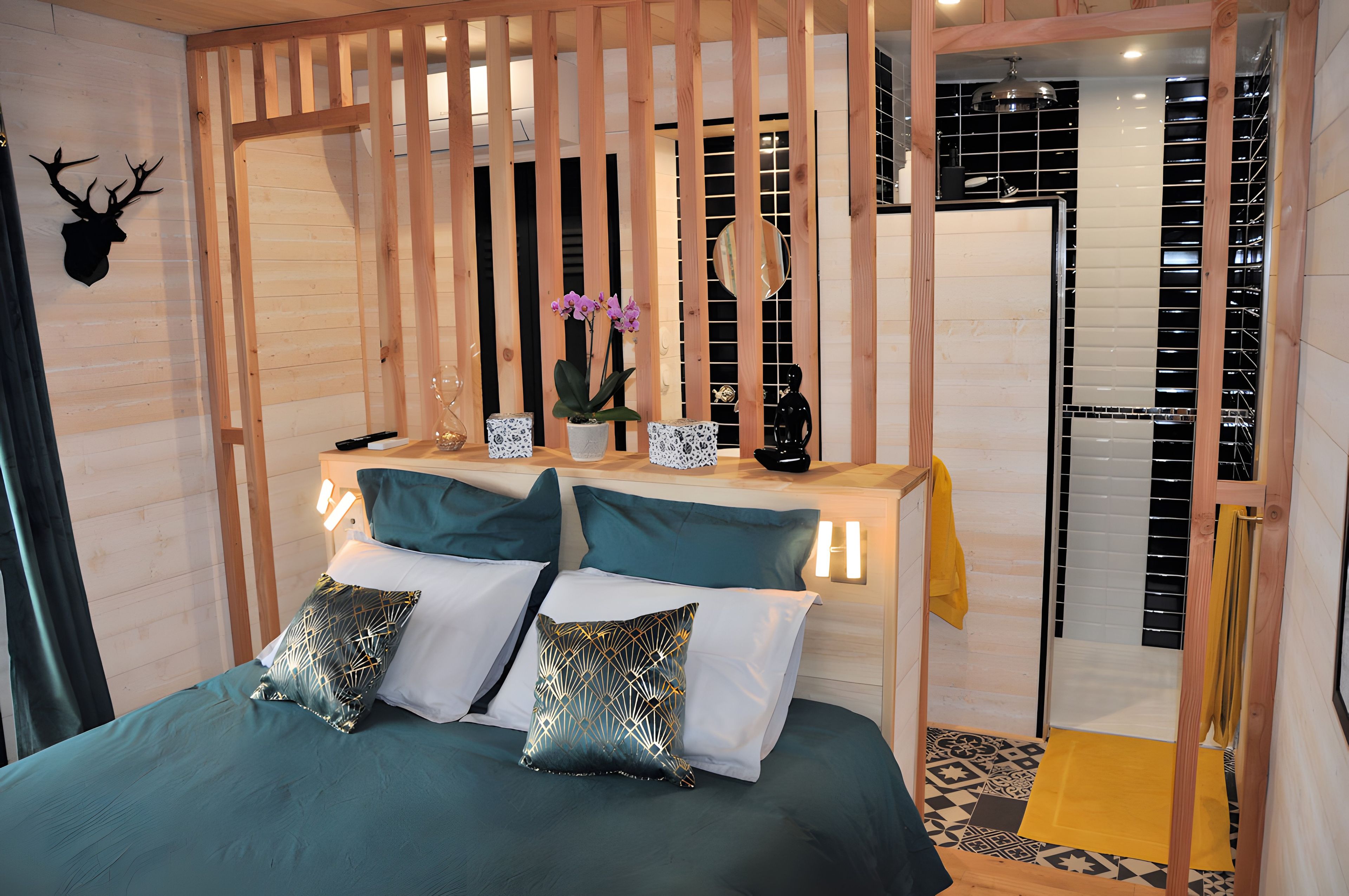 A room with a bed, a nightstand, a mirror, and a door.