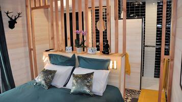 A room with a bed, a nightstand, a mirror, and a door.