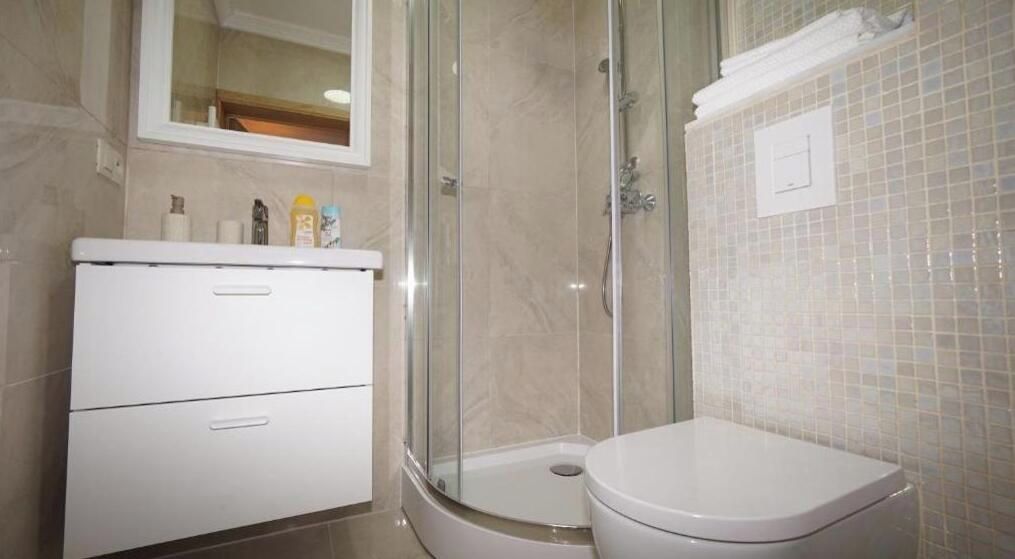 Une salle de bain avec une douche à parois de verre, des toilettes et un meuble contenant des articles de toilette.