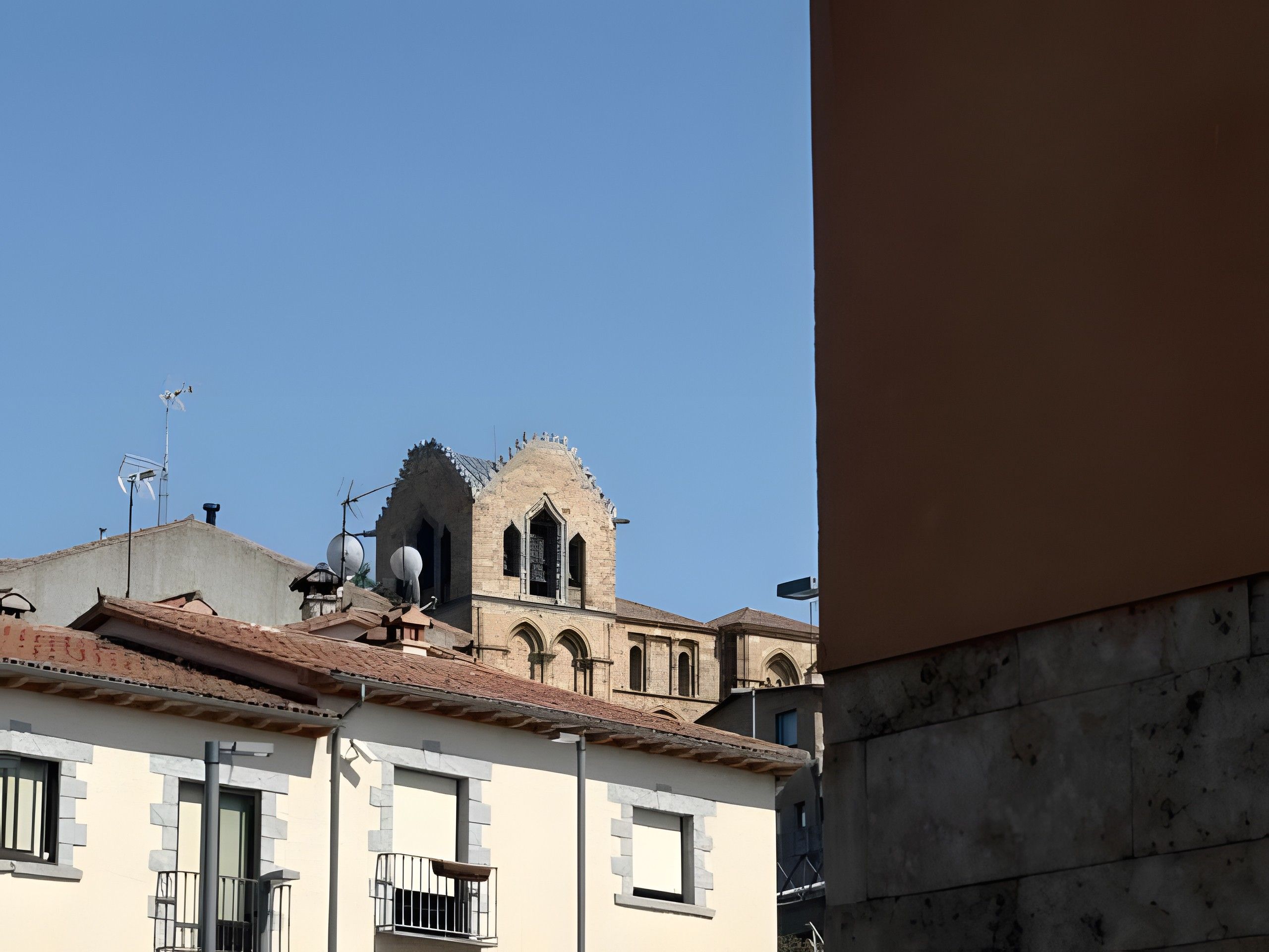 A building with a distinct arched tower and a flat-roofed structure with visible balconies.
