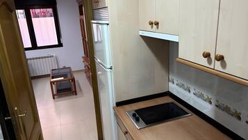 A kitchen with a built-in stove, cabinets, and a window with curtains.