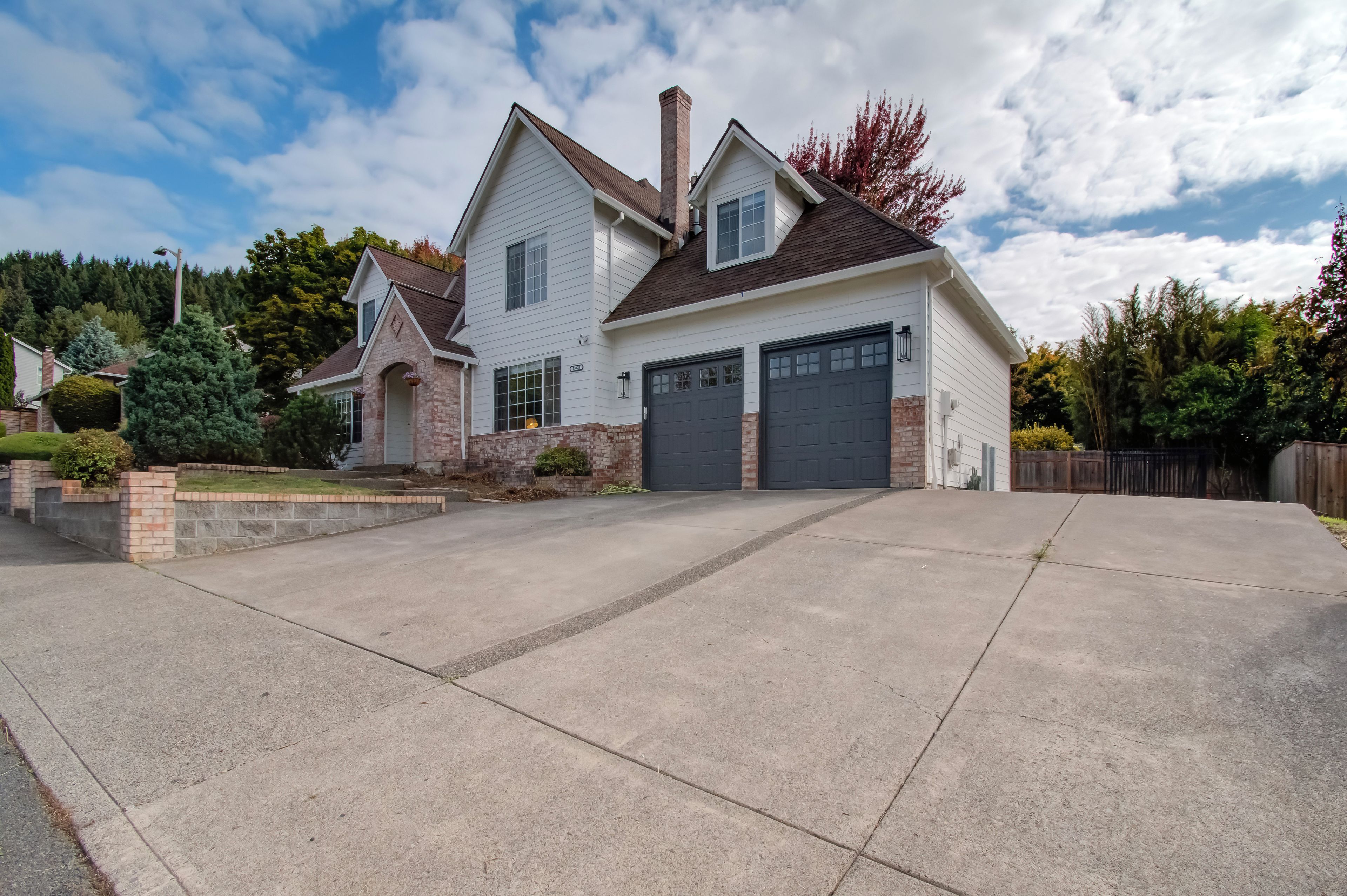 Une maison à deux étages avec un garage, une allée et une pelouse bien entretenue.