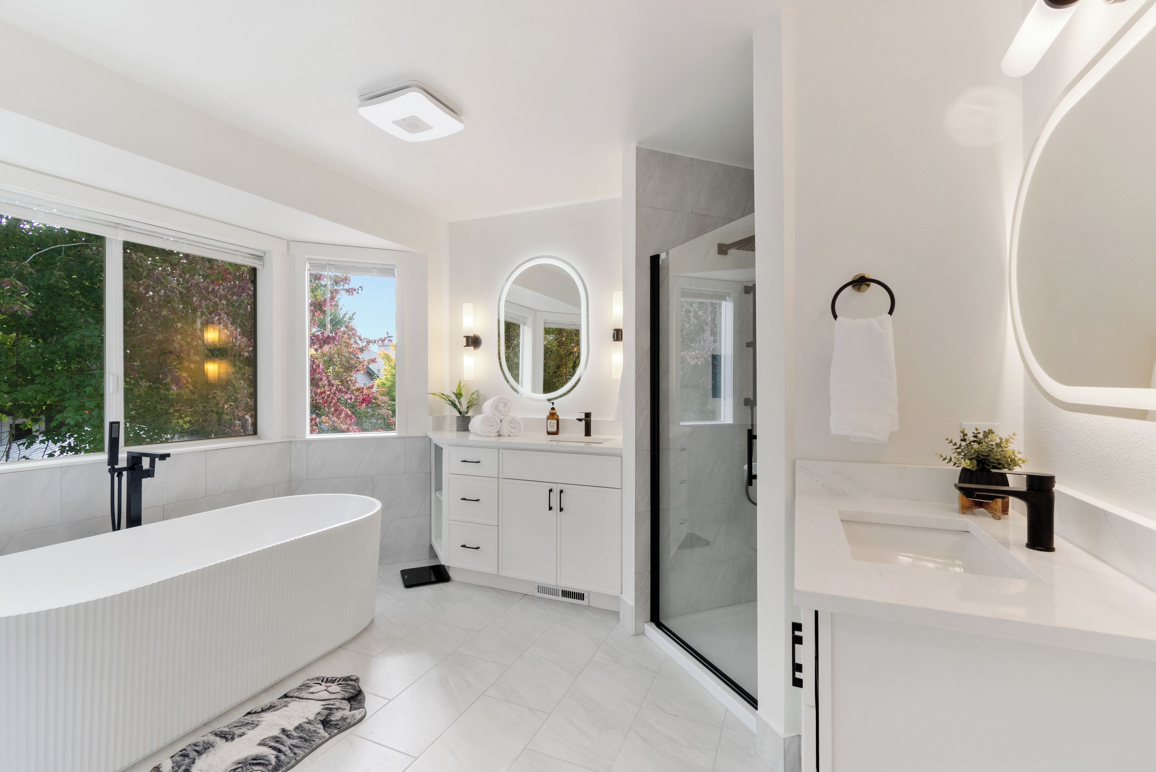 A modern bathroom with a large bathtub, a walk-in shower, and a vanity with a mirror.
